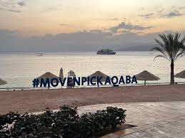 A beautiful view of the Mövenpick Hotel in Aqaba from the beach, with clear blue waters and the hotel’s elegant architecture in the background.