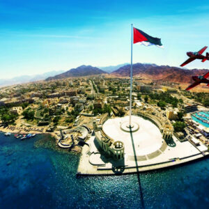 "View of Aqaba from above, showcasing the coastline, city, and surrounding mountains."